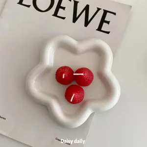 Ceramic flower plate detail with strawberry candles, aesthetic table setup for food styling.