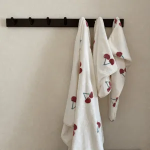 Soft fluffy cherry print white dry hair cap and bath towel hanging detail closeup view.