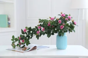 Detailed view of artificial pink rose vine flowers in a blue ceramic vase for home decor.