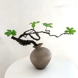 Vue détail de la branche de fleur de prunier artificielle chinoise bonsaï dans un vase en céramique.