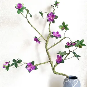 Ramo di fiori di azalea artificiale con steli flessibili e fiori viola in un vaso grigio.