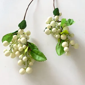 Close-up detail of artificial white berry branches with green leaves, perfect floral decor.