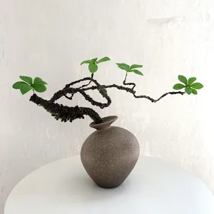 Chinesischer künstlicher Bonsai-Zweig mit grünen Blättern und Keramikvase für Dekoration.