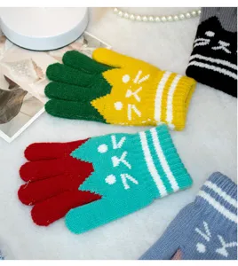 Close-up detail of colorful children winter warm knitted gloves featuring cute cat face pattern.