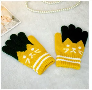 Close-up detail of kids knitted gloves featuring lovely cat face pattern for winter warmth.