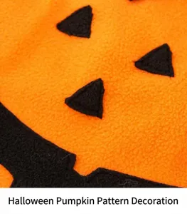 Close-up of orange fleece pumpkin pet costume fabric and black facial patch details for Halloween.