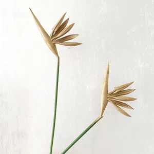 Detailed close-up view of artificial golden bird of paradise flower with green stem decor.