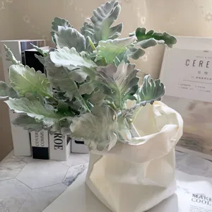 Detailed close-up of artificial flocked dusty miller leaf bouquet in white decorative pot.