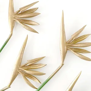 Close-up of golden artificial bird of paradise flowers with green stems for home decor.