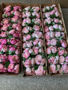 Close up of artificial pink peony silk flower bundles neatly packed in cardboard boxes.