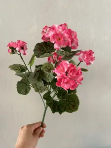 Close-up detail of artificial pink flower bouquet showing realistic petals and green leaves for decoration.