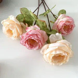 Detailed close-up of artificial vintage silk roses with burnt edges and delicate green leaves.