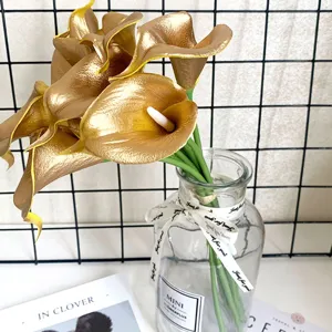 Close-up van gouden kunstmatige calla-lelies in glazen vaas voor interieurdecoratie.