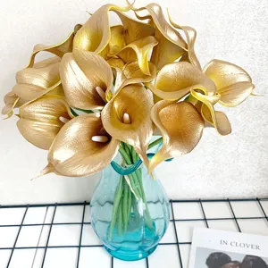 Close-up van gouden kunstmatige calla-lelies boeket in blauwe glazen vaas, interieurdecoratie.