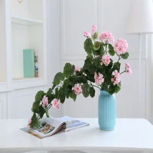 Artificial flower vine for home decoration, pink faux flowers with green leaves in blue vase.