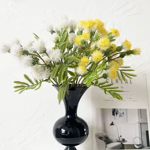 Artificial dandelion flower bouquet with yellow and white spheres and green leaves in black vase.
