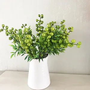 Rami di bacche verdi artificiali in un vaso di ceramica bianca per la decorazione della casa.