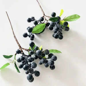 Artificial berry branch detail showing realistic dark fruit and green leaves for floral decor.