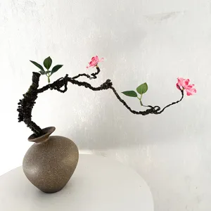 Nahaufnahme eines künstlichen Pflaumenblütenzweigs mit Keramikvase für elegante Deko.