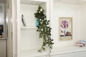 Detailed view of artificial rose hanging vine with lush green leaves in home decor setting.