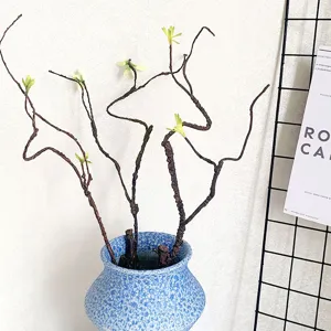 Nahaufnahme von künstlichen Ästen mit grünen Knospen in einer blauen Keramikvase Deko.