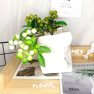 Detail view of artificial berry flower arrangement in white fabric pot for Nordic home decor.