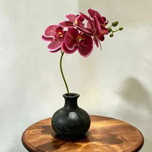Kunstmatige phalaenopsis orchidee in zwarte keramische vaas bloemstuk woondecoratie