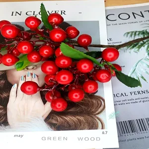 Close-up detail of artificial red berries branch with green leaves for home decor scene.