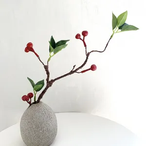 Ramo di fiori finti con bacche rosse e vaso in ceramica per decorazioni d'interni casa.