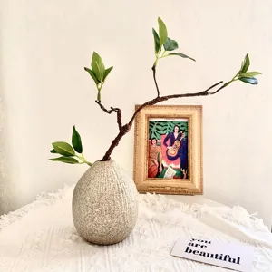 Detail view of decorative ceramic vase with artificial branch, modern home floral decor setup.
