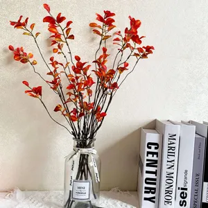 Kunstmatige esdoornbladeren in heldere glazen vaas, herfstdecoratie voor huisinrichting.