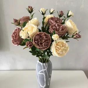 Vista dettagliata del bouquet di rose e peonie artificiali in vaso di ceramica grigia.