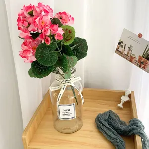 Detail view of artificial pink begonia flowers in a clear glass vase for home decor.