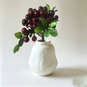 White ceramic vase with artificial red berries bouquet for home desktop decor and interior display