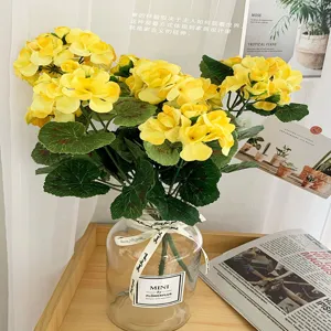 Detail shot of artificial yellow flower bouquet in glass vase for interior wedding decor.