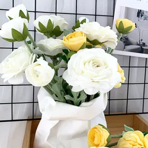 Detailaufnahme eines künstlichen weiß-gelben Kamelienblumenstraußes in moderner Papiervase.