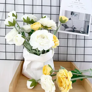 Nahaufnahme eines künstlichen weiß-gelben Kamillenblumenstraußes in einer weißen Papiertüte.