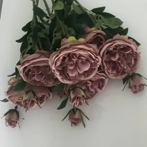 Primo piano dettagliato di un bouquet di peonie artificiali rosa vintage con foglie verdi.