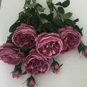 Vista dettagliata di rosa artificiale, tonalità viola vintage con foglie verdi per decorare.