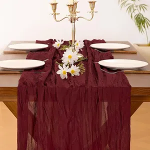 Burgundy cheesecloth table runner detail, wrinkled gauze fabric for wedding party decor.