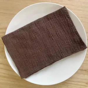 Close-up detail of the brown wrinkled napkin on a white ceramic plate, perfect for western table decor.