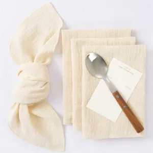 Close-up detail of cream wrinkled table napkins with wooden handle spoon and decor card for decor.