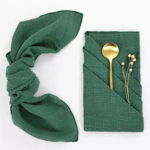 Dark green crinkle fabric napkin detail, elegant tableware setup for wedding party table decor.
