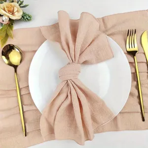 Detailed view of textured wrinkled table napkin and elegant gold cutlery set for dining table decor.