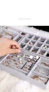 Detalle de bandeja de joyería de terciopelo gris, organizador multi-rejilla anillos.