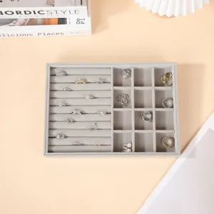 Organizador de bandeja de joyería de terciopelo gris con ranuras para anillos y rejillas.