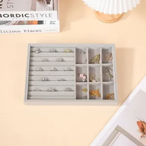 Bandeja de terciopelo gris para joyas con ranuras para anillos y compartimentos para collares.