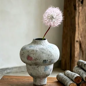 Detailed view of a unique decorative vase with a pink artificial dandelion flower.