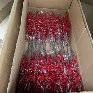 Detail view of artificial red berry branches, neatly packed in a cardboard box for wholesale.