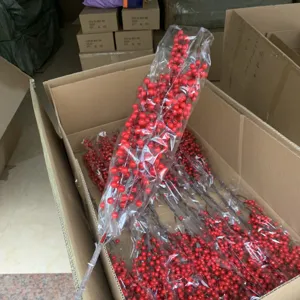 Detailed view of bulk artificial red winterberry branches in packaging box for decor.